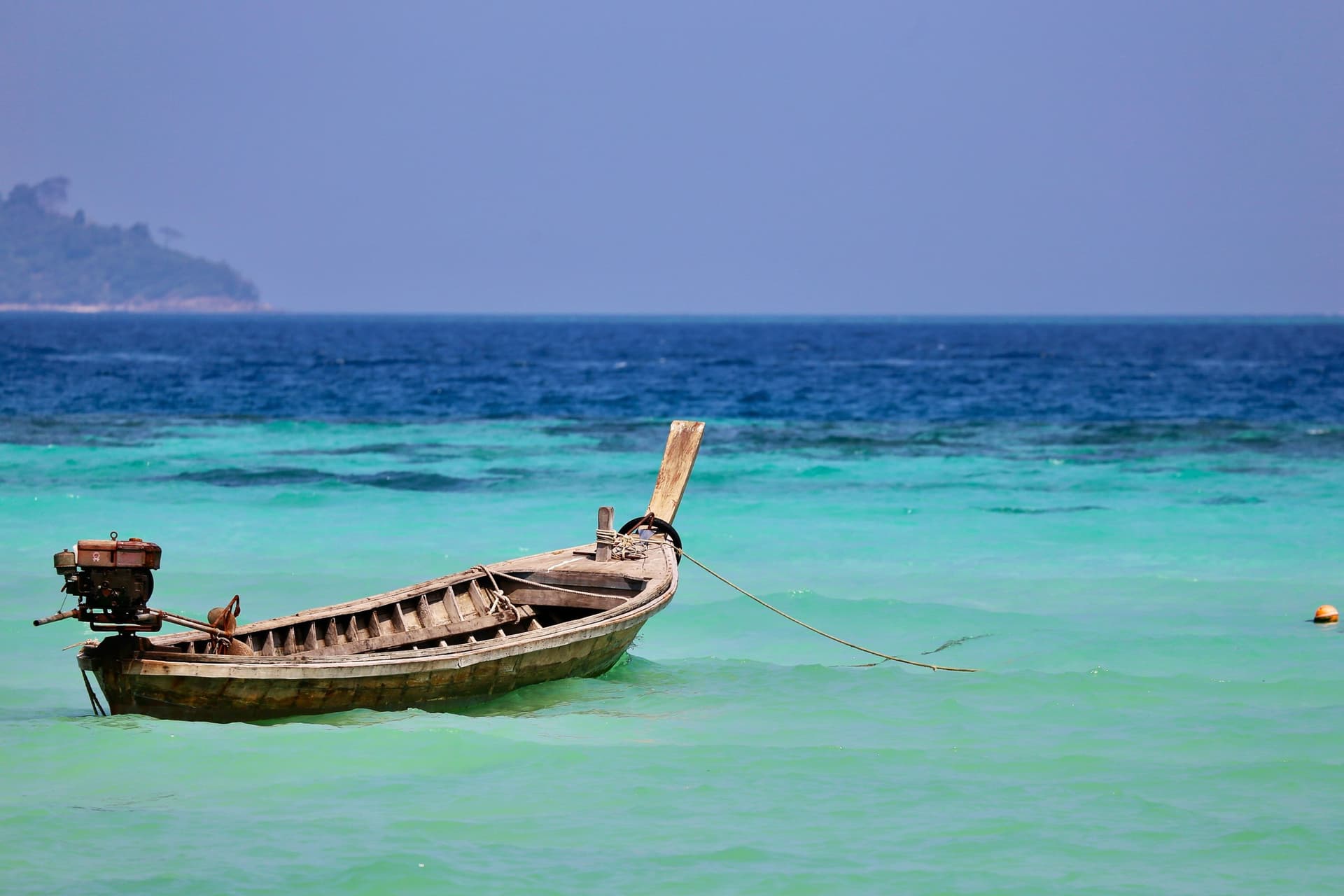 An empty longtail moored offshore in Thailand. A private boat for the group costs more than a seat on a shared one, and a quote should say which you are getting.