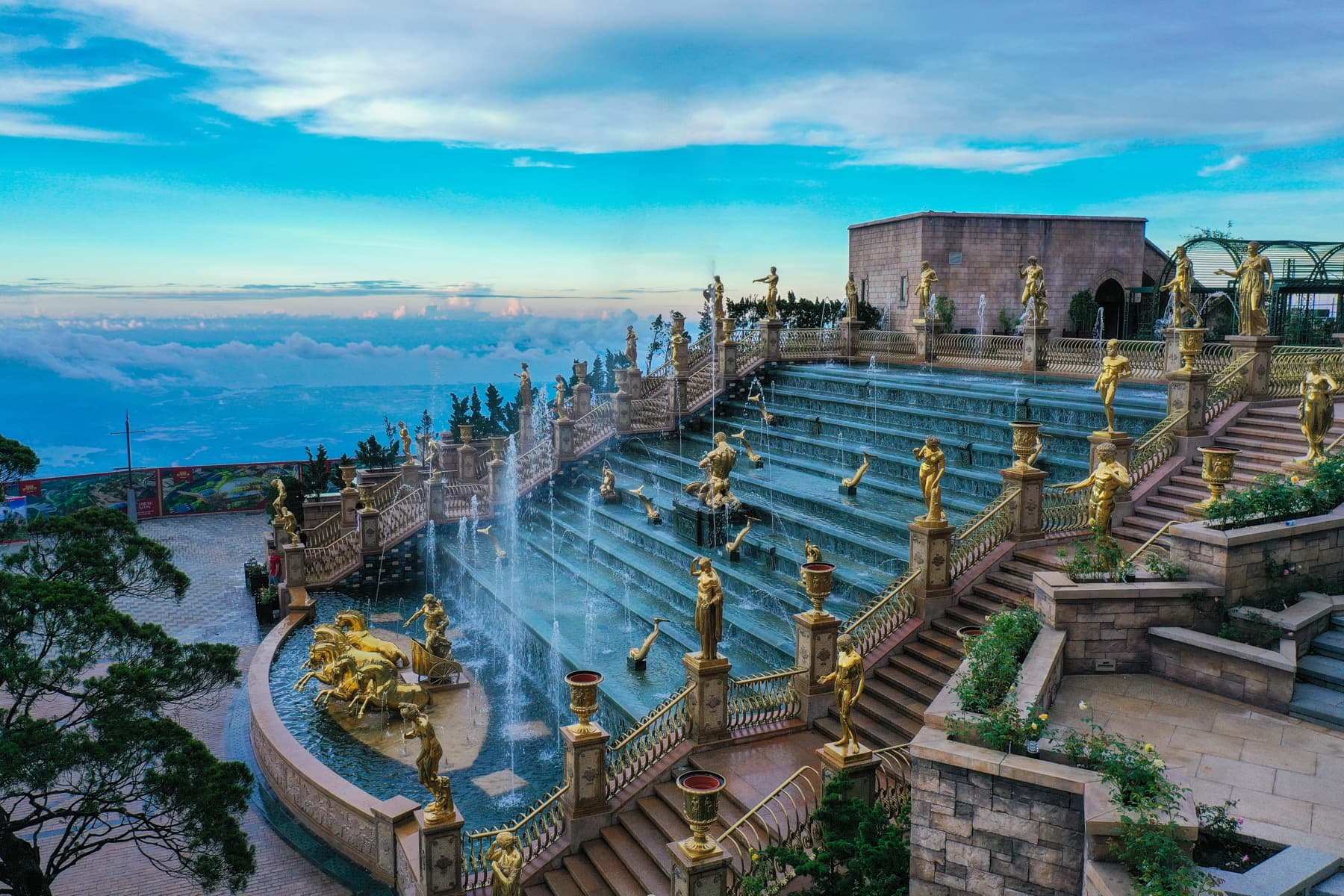 Hilltop Thai temple complex with golden statues and infinity pool overlooking valley — northern Thailand
