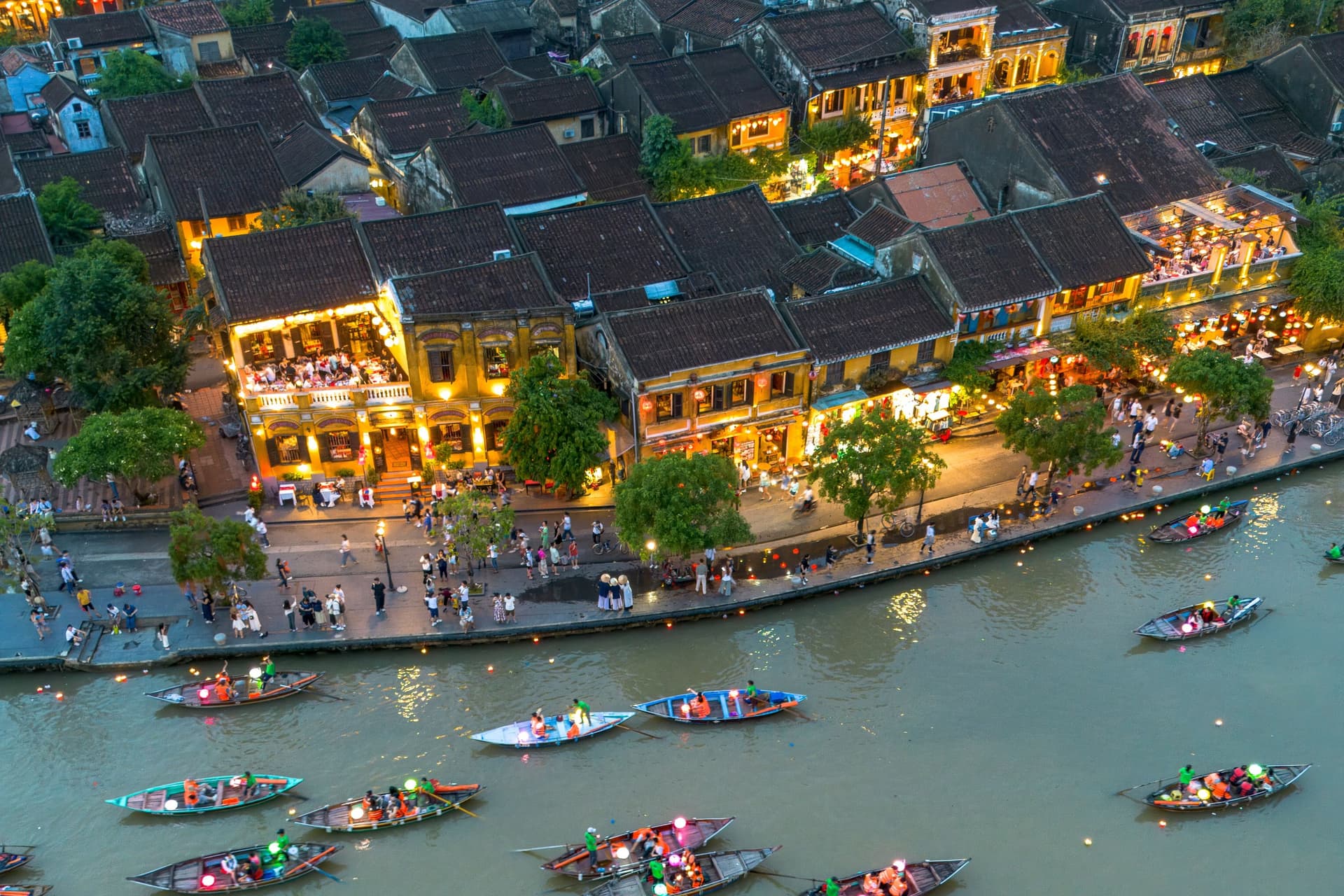 Hoi An's ancient town at dusk, lantern light over the tiled rooftops, a central anchor of the south-to-north route.