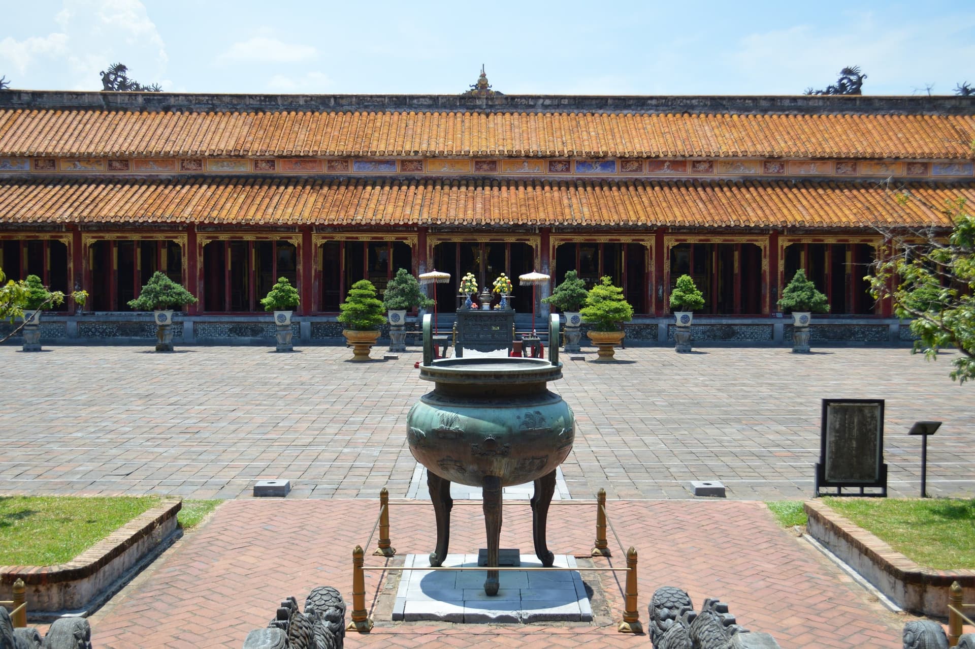 A bronze dynastic urn in the courtyard of the Imperial City at Hue, the tiled colonnade behind it.