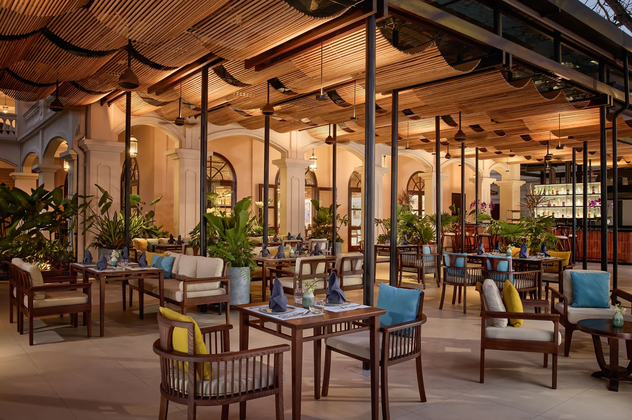 Tables laid on the covered terrace of Art Space Restaurant & Bar, with arched doors and a lit bar behind