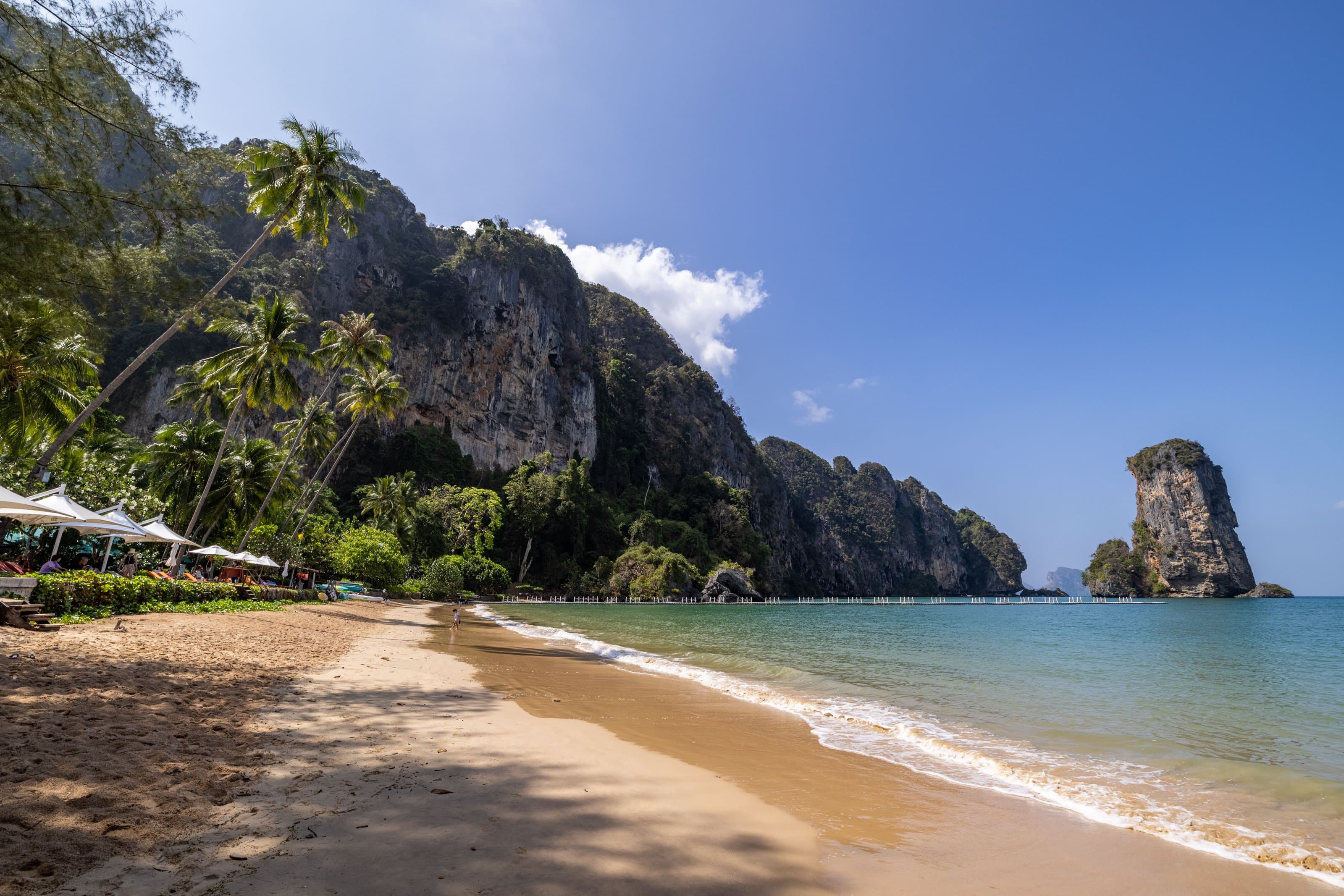 Ao Nang beach under limestone cliffs, with a karst islet offshore