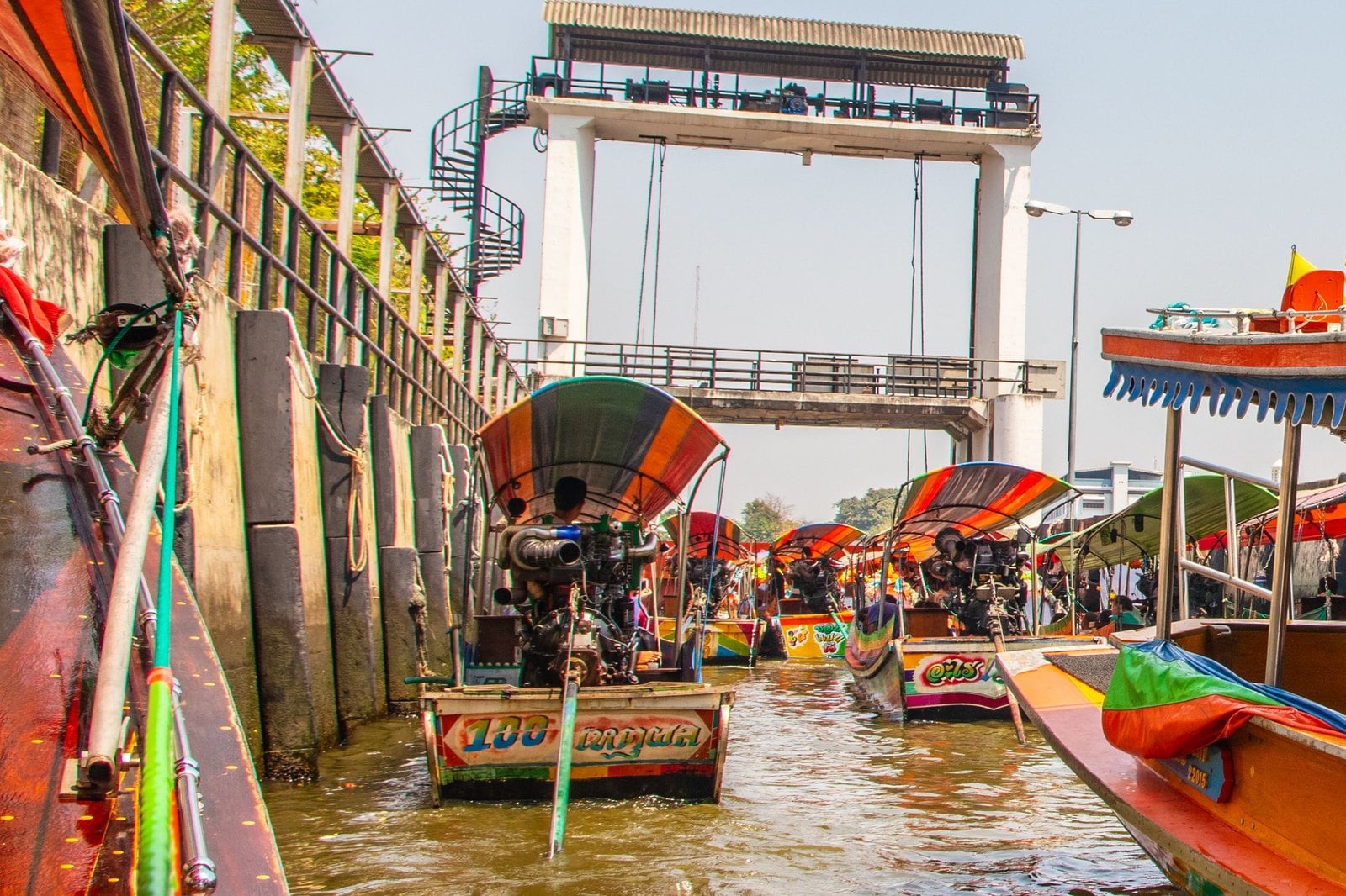 Perahu-perahu longtail yang dicat berjajar di pintu air sebuah kanal di Bangkok