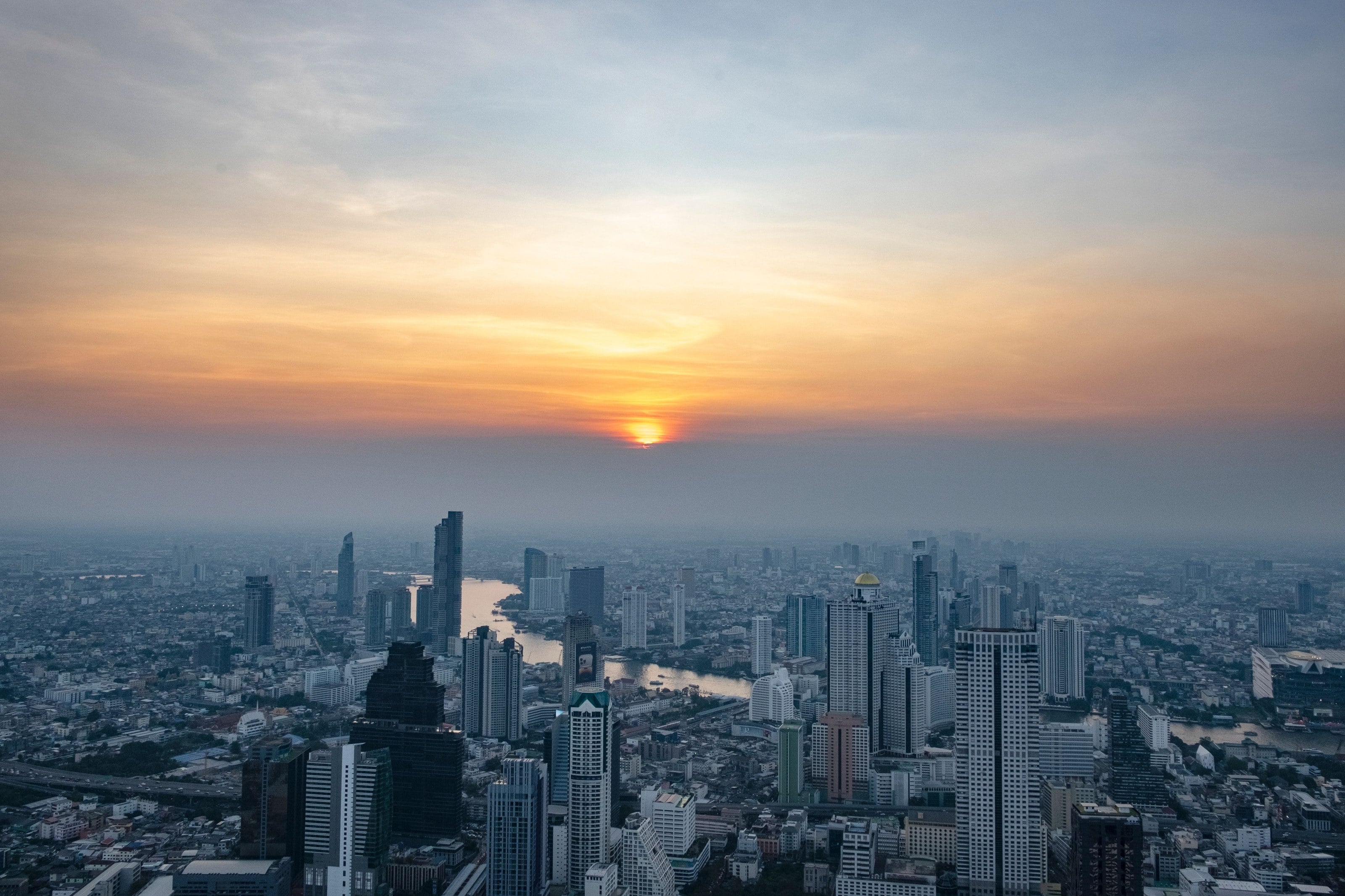 Pemandangan Bangkok dari atas, dengan Sungai Chao Phraya di bawah langit senja.