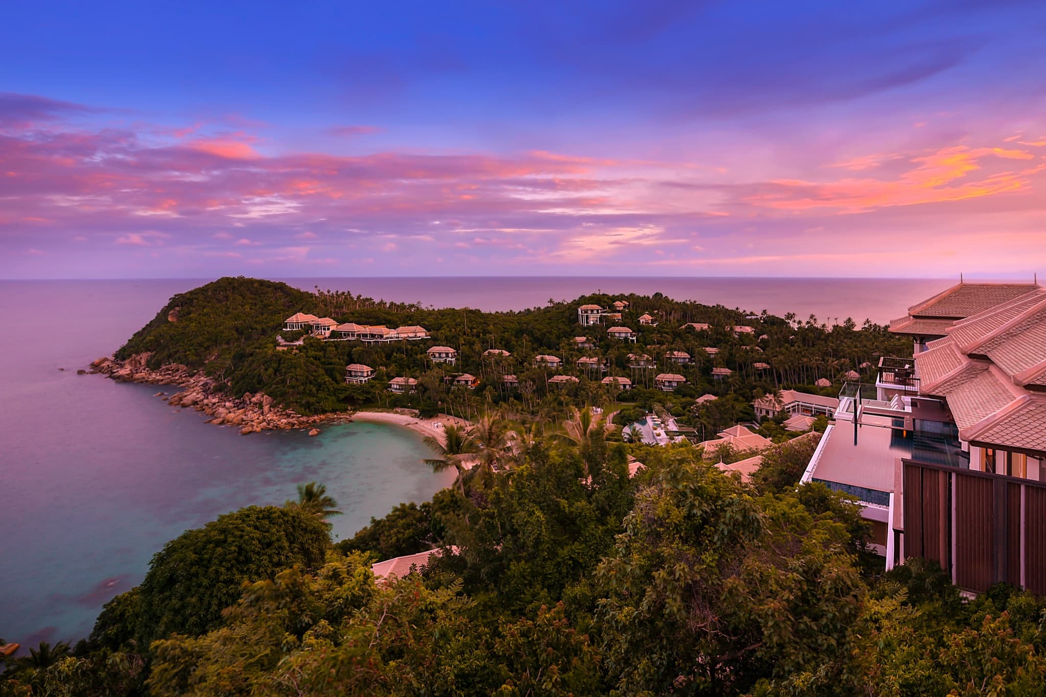 A hillside resort of pool villas above a turquoise bay at sunset, Koh Samui, Thailand
