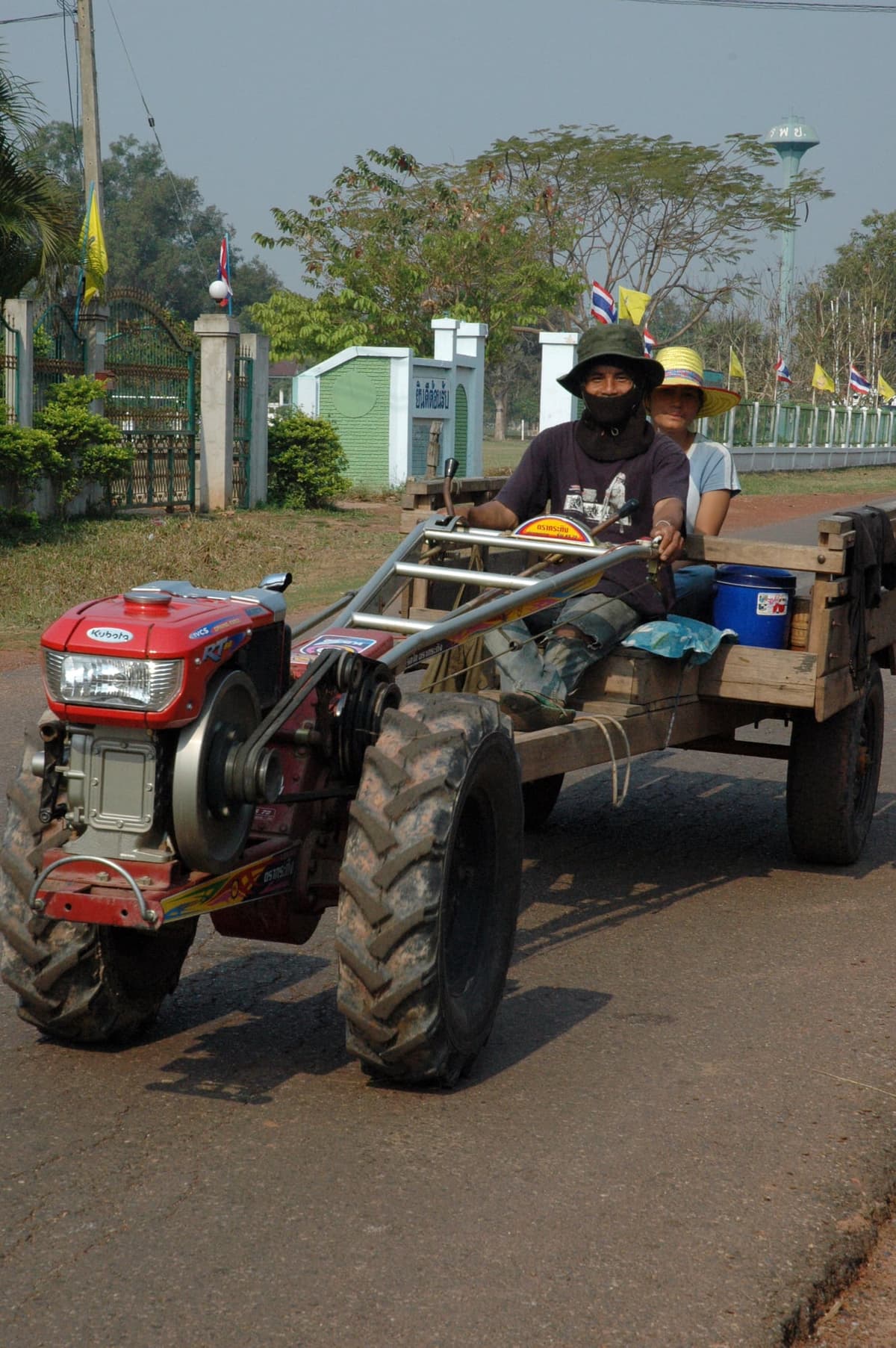 An e-taek, the single-axle Isan farm tractor, rigged with plank seats and a trailer for the ride out to the forest.