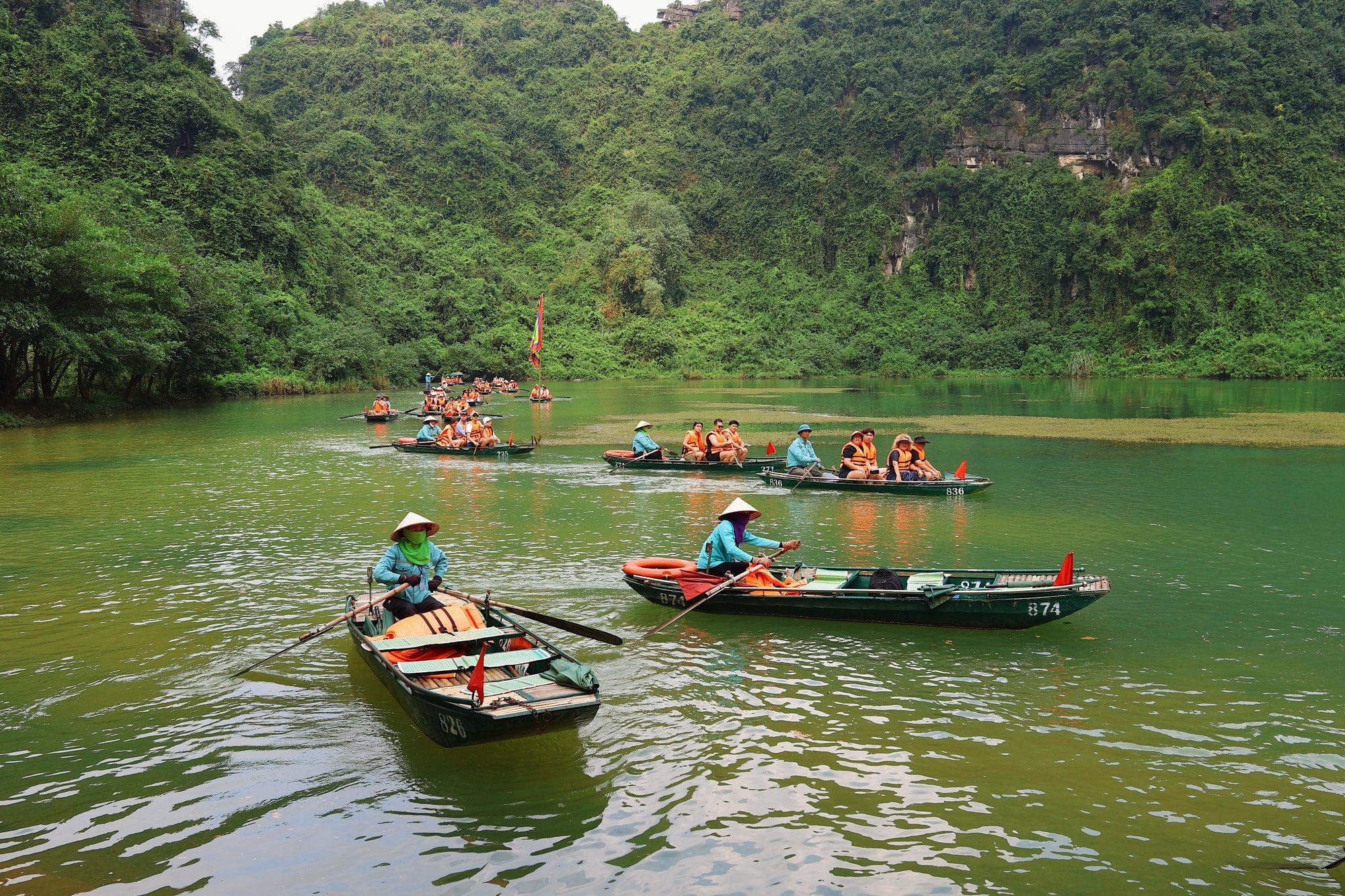 قوارب تجديف تحمل الزوار على نهر بين قمم من الحجر الجيري في هوا لو (Hoa Lu)، نينه بينه (Ninh Binh)