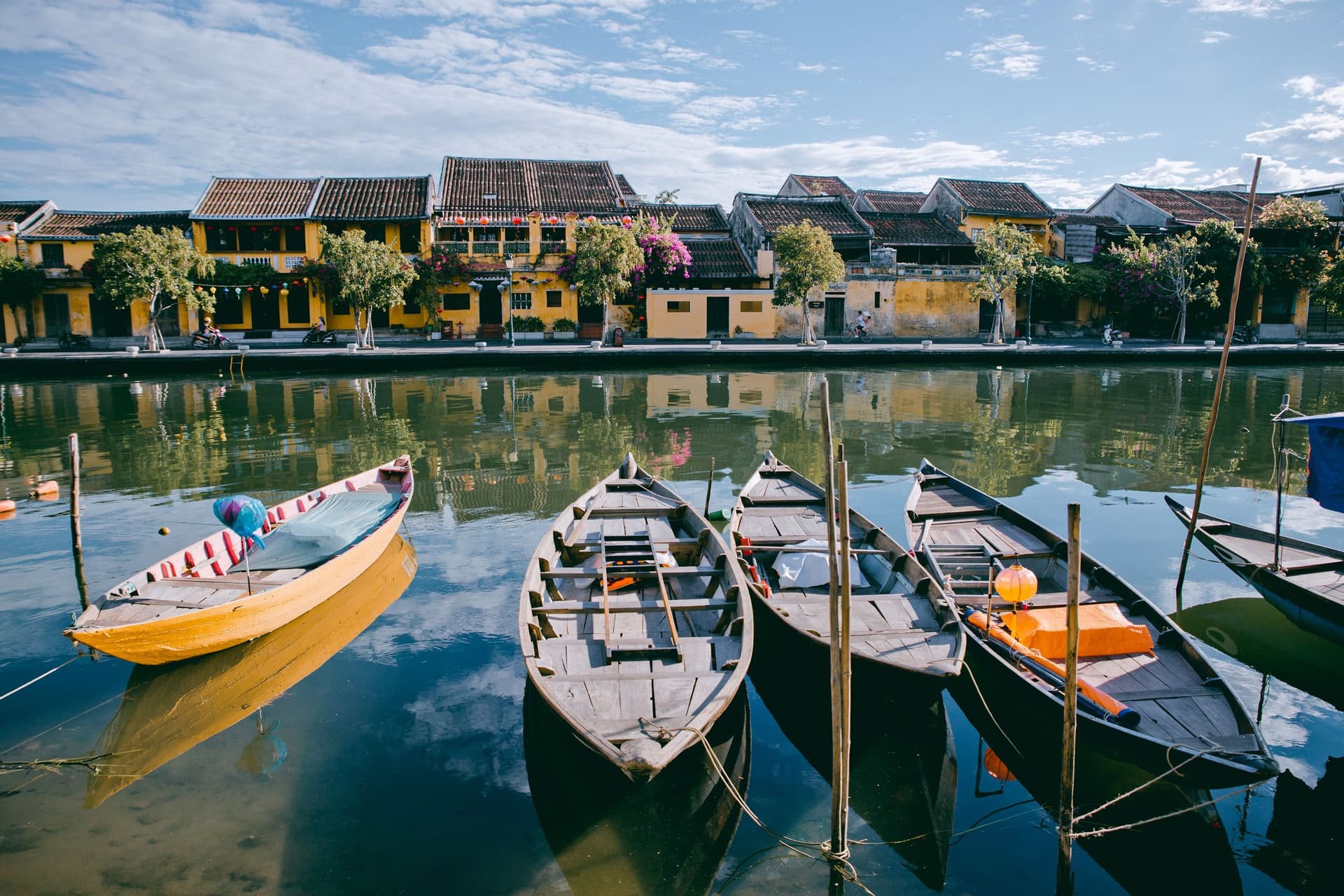 Wooden boats moored on the Thu Bon river below the shophouses of Hoi An.