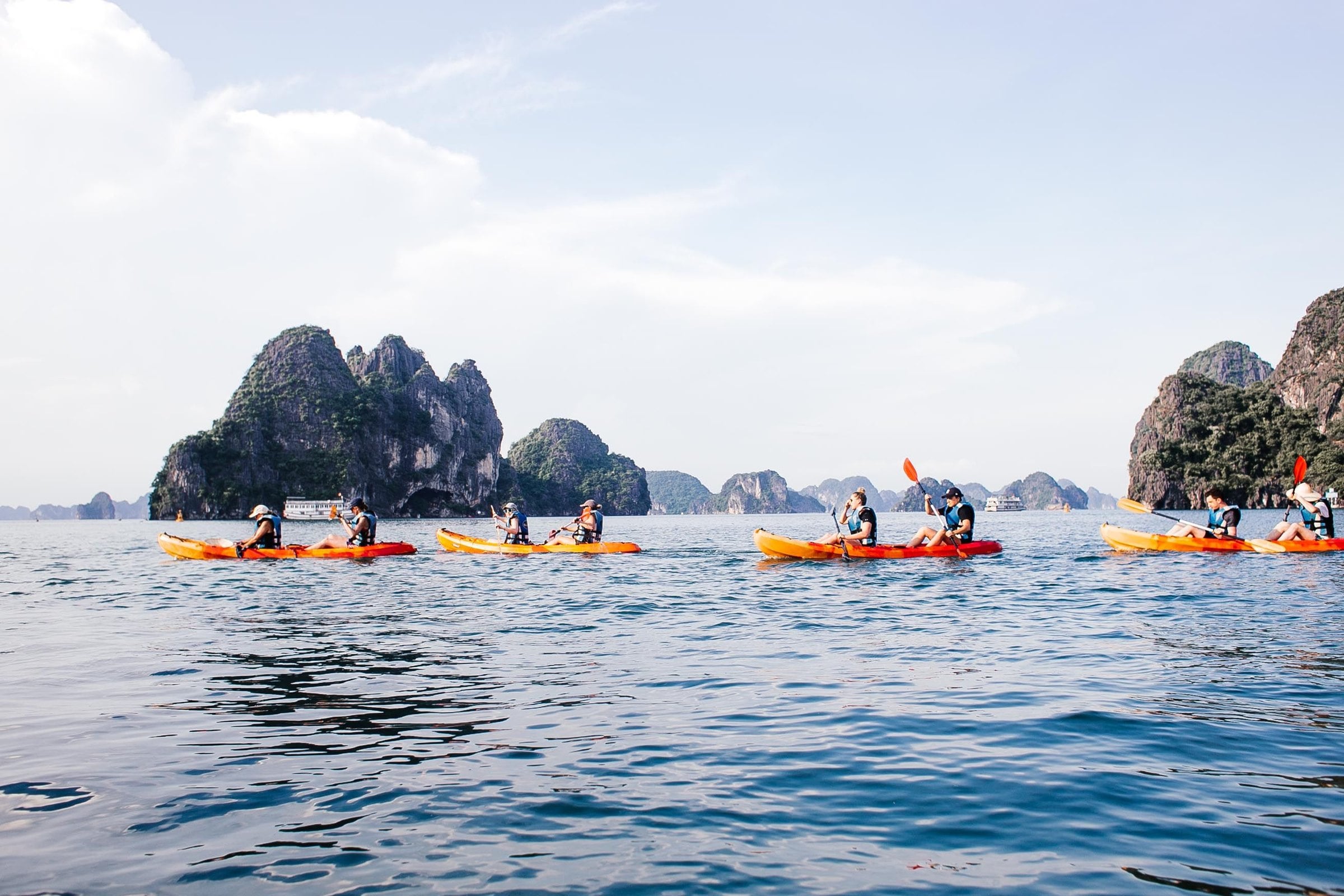 Personas en kayak que reman en fila entre islas de piedra caliza, sobre aguas tranquilas