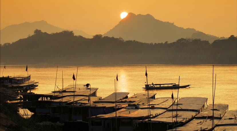 Sunset over the Mekong at Nong Khai, boats moored along the bank and the hills of Laos on the far side.