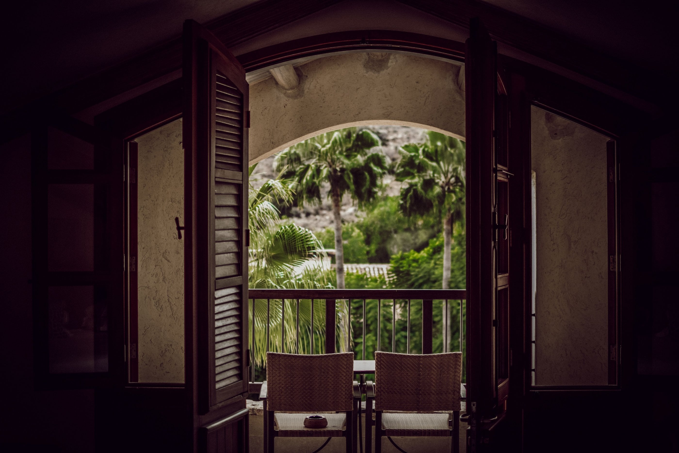 An arched interior opening onto a palm-shaded balcony, a northern highland suite.