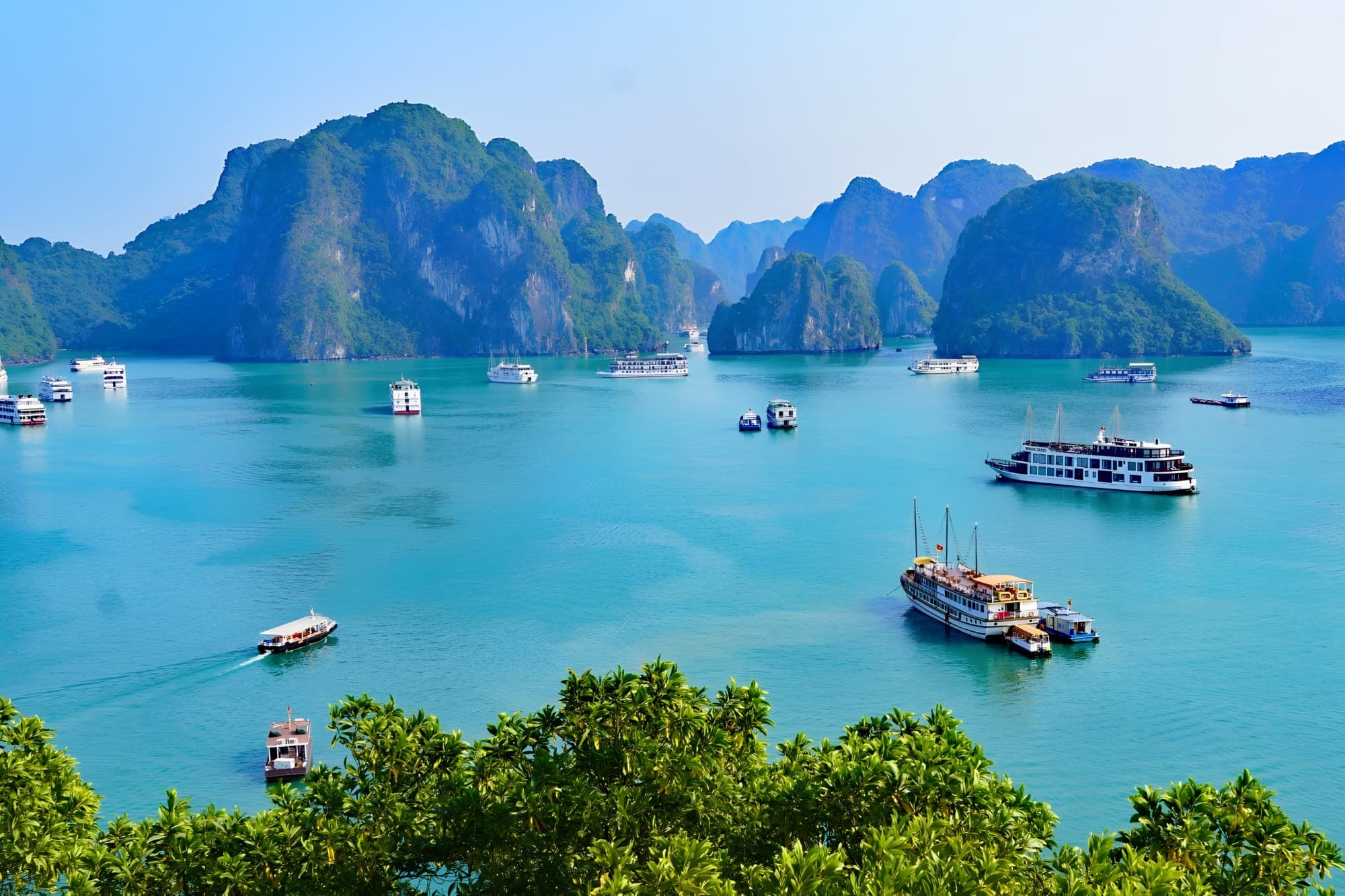 A traditional cruise boat on the emerald waters of Ha Long Bay among limestone karst islands, Vietnam