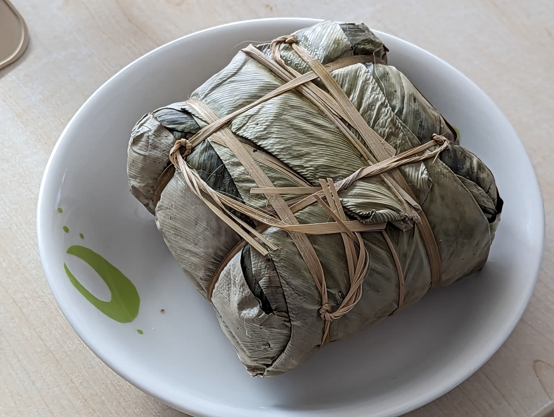 A leaf-wrapped square banh chung rice cake on a plate.