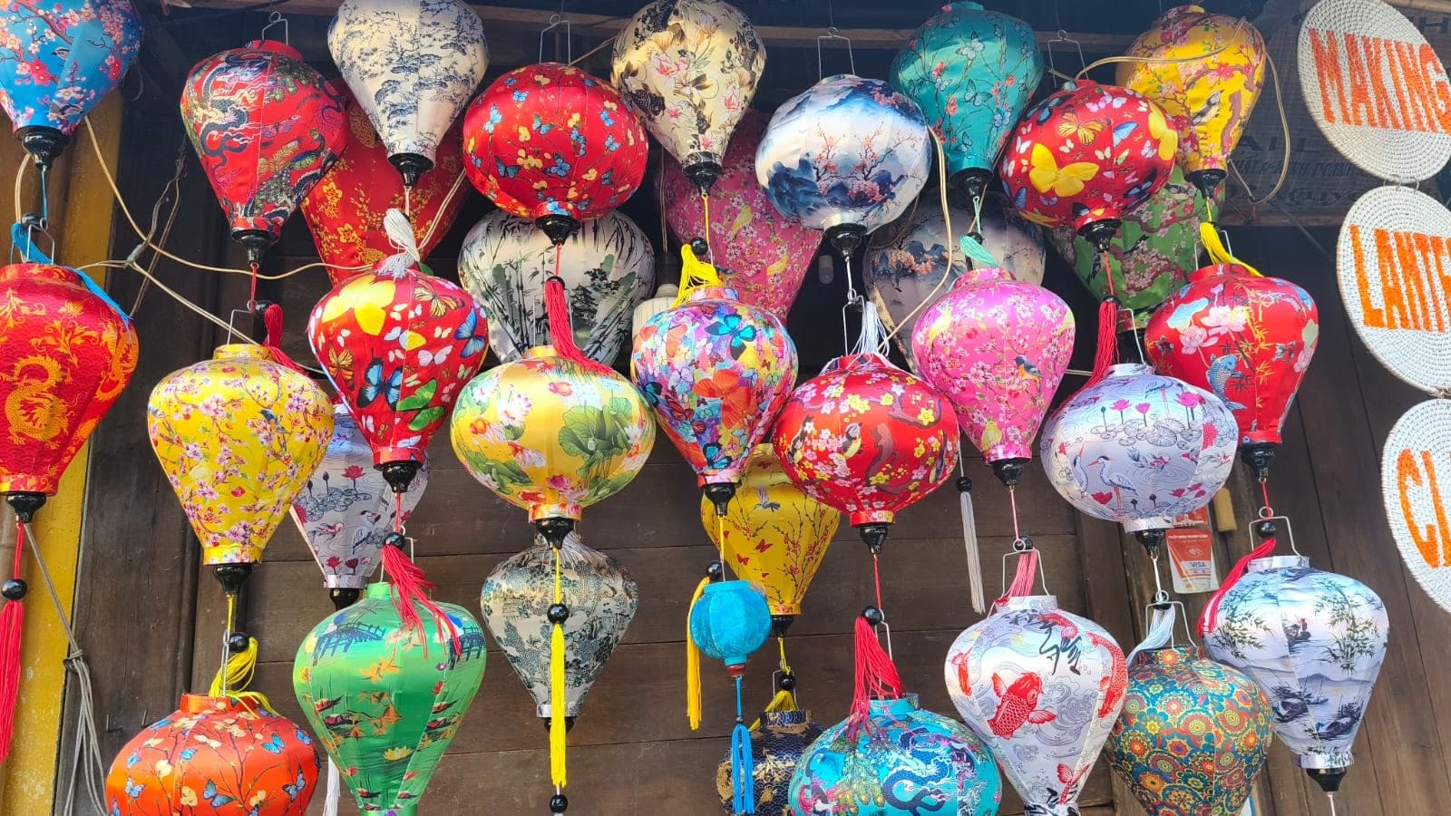 Những chiếc đèn lồng nhiều màu vẽ hoa, chim và phong cảnh treo cạnh nhau
