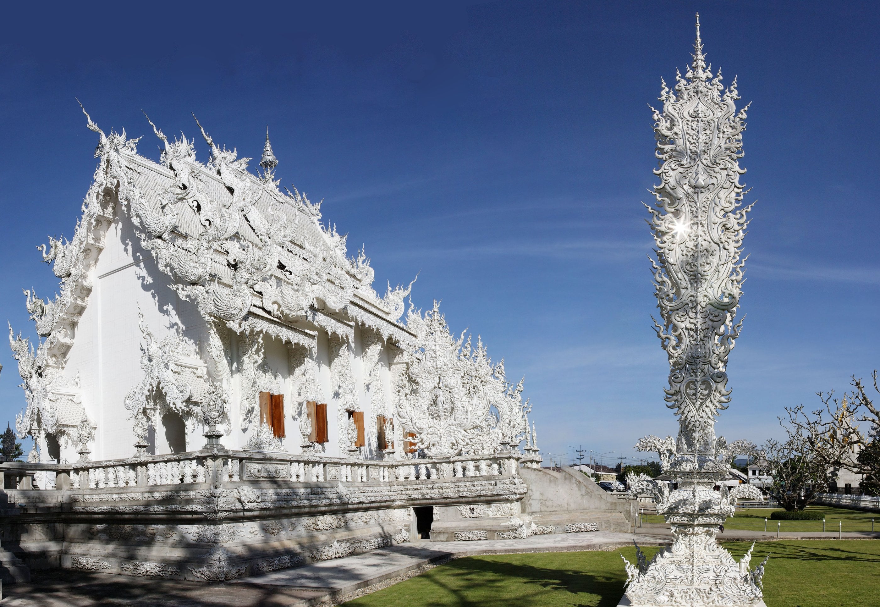 Wat Rong Khun, Chiang Rai's dazzling white contemporary art temple, mirrored in its reflecting pool.